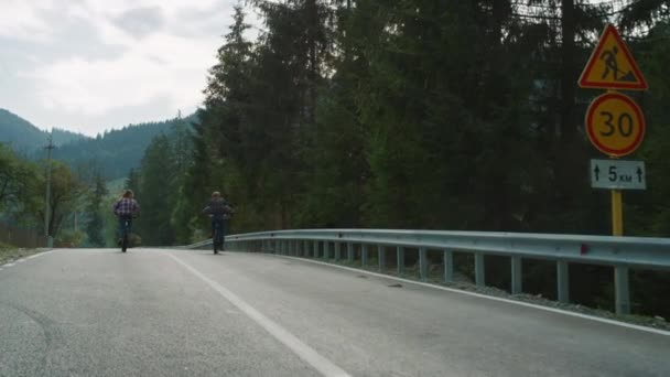 고속 도로에서 자전거를 타는 커플이에요. 산에서 자전거를 타는 여행자들 — 비디오