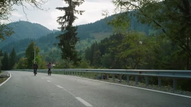A kerékpárosok együtt bicikliznek a hegyi úton. Két barát szereti a sportot.. — Stock videók