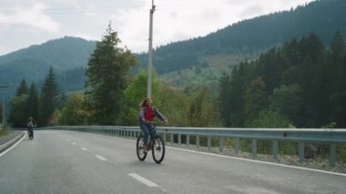 Arkadaşları spor bisikletleriyle orman yolunda bisiklet sürüyor. Kaygısız gezginler dağların keyfini çıkarırlar..