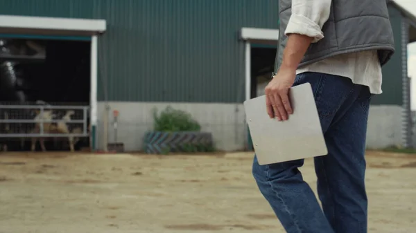 Farm worker walking livestock facility. Hand holding clipboard legs closeup. — Stockfoto