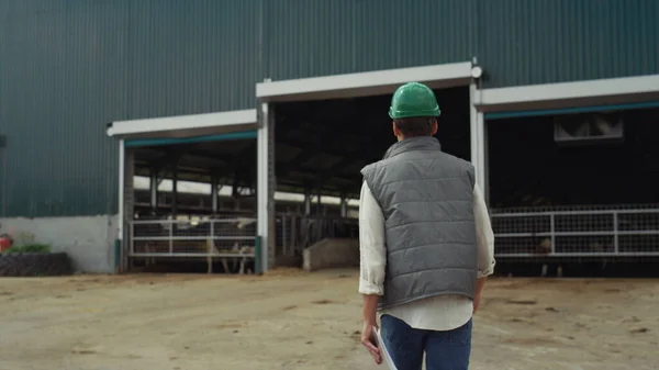 Farm breeder walking modern cowshed rear view. Agriculture facility building — ストック写真