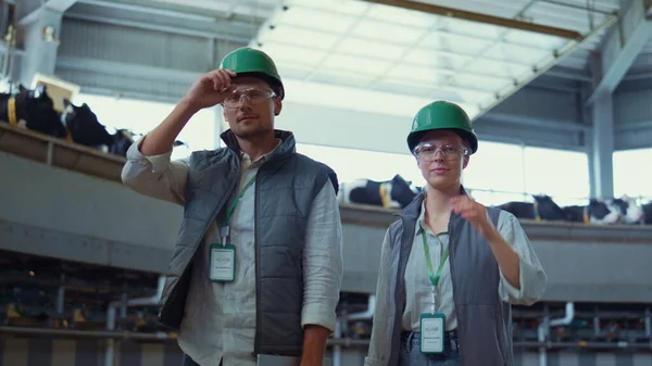 Farmers posing dairy farm facility portrait. Smiling workers taking off helmets. — стоковое фото