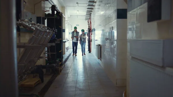 Factory engineers walking production facility. Supervisors discuss milking plans