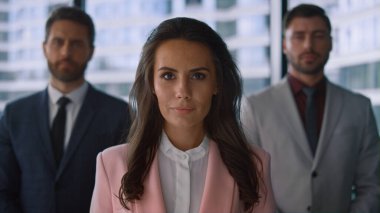 Modern ofiste kameraya poz veren hırslı iş adamları. Takım çalışması konsepti