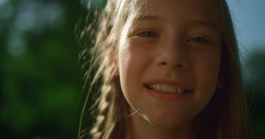 Altın güneş ışığında poz veren neşeli sarışın kız. Kameraya bakan neşeli çocuk. 