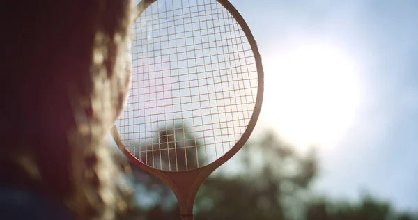 Zbliżenie dziewczyna sylwetka patrząc słońce przez badminton rakieta netto w letni park. — Zdjęcie stockowe