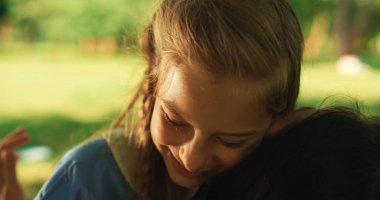 Gülen kız piknikte annesine sarılıyor. Çocuklar annelerini sever..