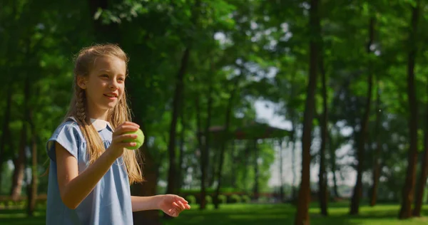 Treinamento menina para jogar bola no parque verde de perto. Criança feliz jogar ao ar livre. — Fotografia de Stock