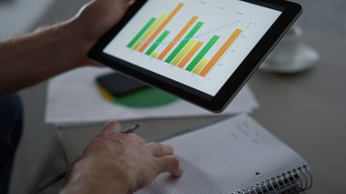Ofis kafesinde dijital tablet aygıtı kullanarak grafik çizelgesi yazan yönetici.