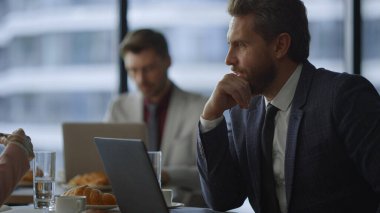Ciddi bir iş adamı kafeteryadaki dizüstü bilgisayarda iş planını tartışıyor..