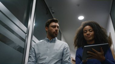 Tablet üzerinde çalışan menajerler ofis koridorunda iş konuşmaya başladılar.