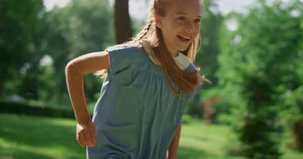 Усміхнена дівчина біжить на м'якій траві. Щаслива дитина грає активну гру на природі . — стокове фото
