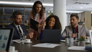 İş dünyası, ofis binasında dizüstü bilgisayarı araştıran fikirleri paylaşıyor..