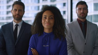 Çok ırklı şirket ekibi vitrin dairesinde kamera karşısında yan yana duruyor..