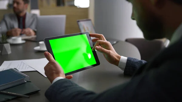 Businessman using tablet device green screen looking corporate news in workplace