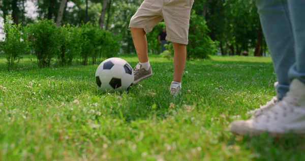 Pernas de menino desconhecidas fazendo exercício de futebol close-up. Filho treinando futebol com o pai. — Fotografia de Stock