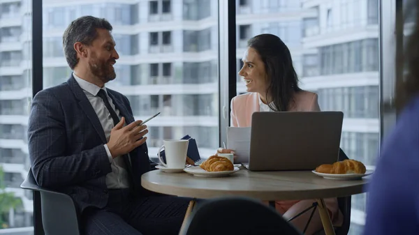 Gledelig par som diskuterer selskapets suksess med laptop på kafe. – stockfoto