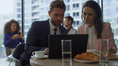 Motivasyonlu iş grubu, kafede dizüstü bilgisayar kullanarak proje başarısını tartışıyor.