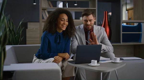 Multiracial entrepreneurs couple video chat using laptop in remote home office.