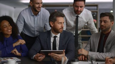 Ofis konferansında finansmanı analiz eden tablet aygıtı kullanan çok ırklı bir ekip.