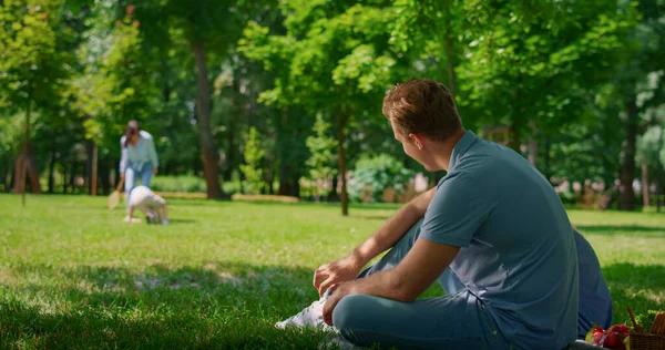 Lächelnder Vater, der auf Familienhintergrund spielt. Aktive Freizeit in der Natur. — Stockfoto