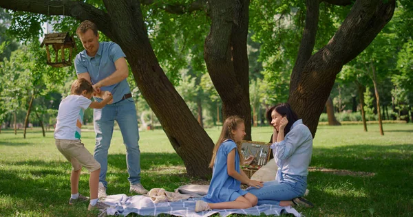 Der Vater hält seinen kleinen Sohn beim Picknick zurück. Eltern spielen im Sommer mit Kindern. — Stockfoto