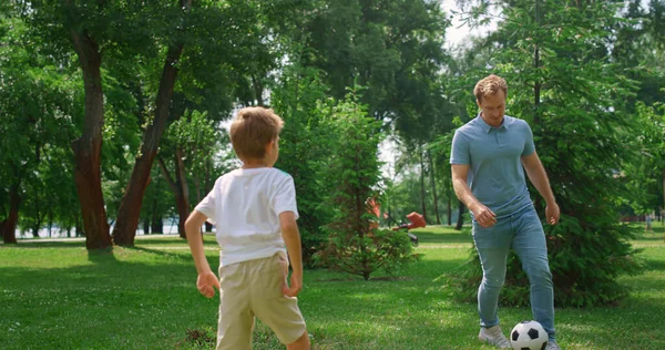 Far spela fotboll med son på grön gräsmatta närbild. Pappa njuta av spelet med pojken. — Stockfoto