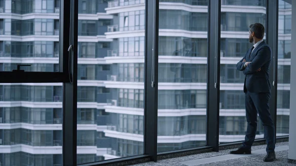 Executive man walking office alone. Young businessman standing looking window.