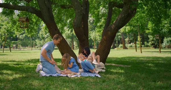 Glada föräldrar kittlar barn på picknick. Familjeunderhållning på sommarhelgen. — Stockfoto