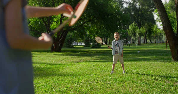 Shuttlecock stuck in racket net. Cheerful kids play badminton in summer park — Stock Photo, Image