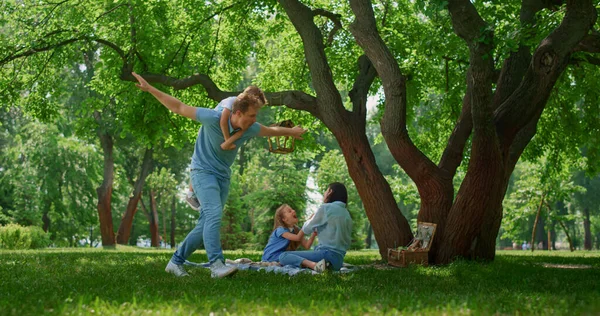 Leende familj har roligt vilar på naturen. Föräldrar leker med barn på picknick. — Stockfoto