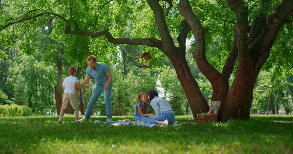 Активная семья веселится на лугу зеленого парка. Родители играют с детьми на улице. — стоковое фото