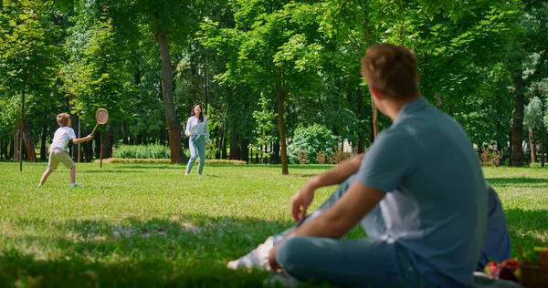 Junger Vater sieht Badmintonspiel verschwommen. Aktivität an der frischen Luft im Park — Stockfoto