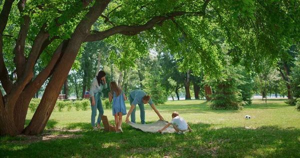 Ung familj picknick på gräsmatta gräs. Föräldrar förbereder lunch med två barn. — Stockfoto