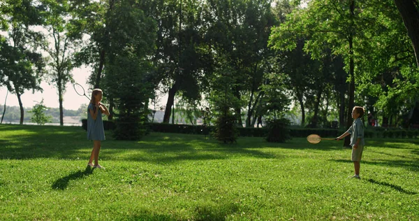 Geschwisterpaar spielt Badmintonschläger im grünen Park. Sommerpicknick — Stockfoto