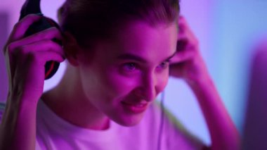 Siber kız pembe neon ışıklara kulaklık takmış. Gülümseyen esport oyuncusu