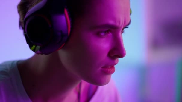 Soustředěná kybernetická dívka hraje počítačovou hru ve sluchátkách detailní up. Esport herní noc — Stock video