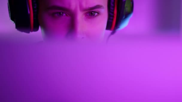 Vacker neon gamer spelar dataspel i rosa neon ljus hemma närbild. — Stockvideo