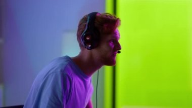 Neon oda kapanışında oyunu kaybeden heyecanlı oyuncu. Üzgün adam kulaklıklarını çıkarıyor.