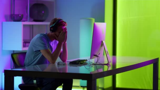 Um tipo triste a perder o jogo de computador na sala de néon. Frustrado gamer sentimento estressado — Vídeo de Stock