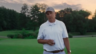 Zengin yaşlılar golf sahasında puro içer. Yaşlı adam dışarıda kameraya bakıyor.