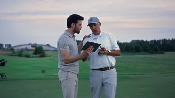 Deportistas modernos sosteniendo tableta web de navegación en el campo de golf. Concepto en línea. — Vídeos de Stock