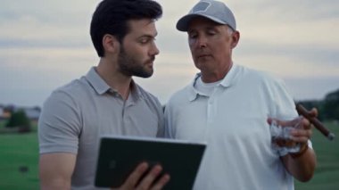 Sahada gezinen iki golfçü. Zengin adamlar teknolojiyi online kullanıyor.