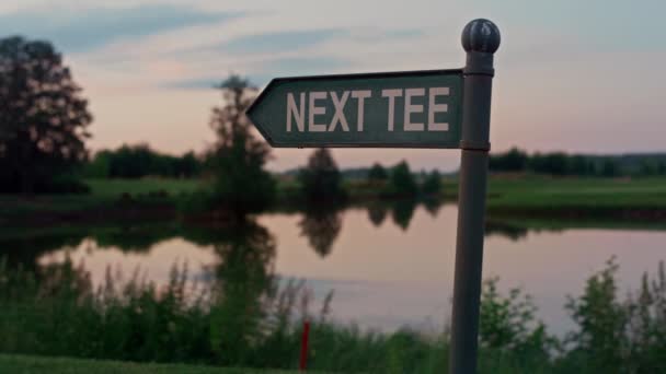 Pole golfowe tee znak w pustym parku golfowym. Pokaż kierunek na zachód słońca natura jezioro — Wideo stockowe