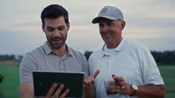 Golfistas sorridentes usando tablet dispositivo falando família on-line no campo clube curso — Vídeo de Stock