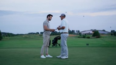 Golf takımı yeşil sahada birlikte savaşıyor. Golf sahasında iki adam tartışıyor.