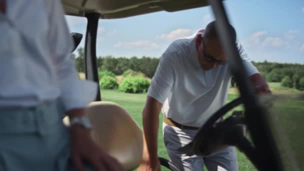 Dos jugadores se sientan carrito de golf en activo fin de semana de verano. Pareja disfrutar de club de campo. — Vídeos de Stock