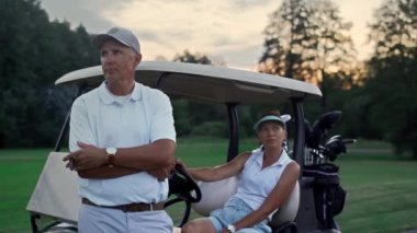 Zengin golf oyuncuları golf arabasında dinleniyor. Spor çifti yaz tatilinin tadını çıkarın..