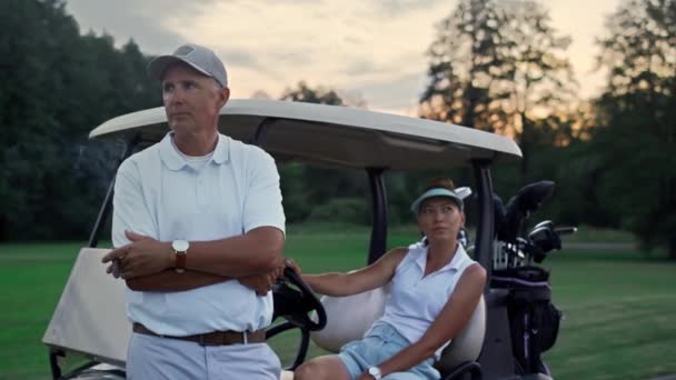 Rijke golfspelers rusten uit bij de golfkar. Sport paar genieten zomer weekend. — Stockvideo