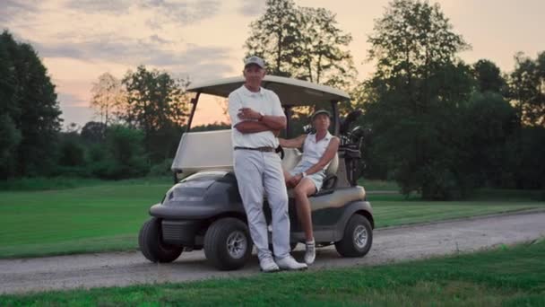 Um par de carros de golfe lá fora. Dois golfistas levam clubes de equipamento desportivo em campo — Vídeo de Stock